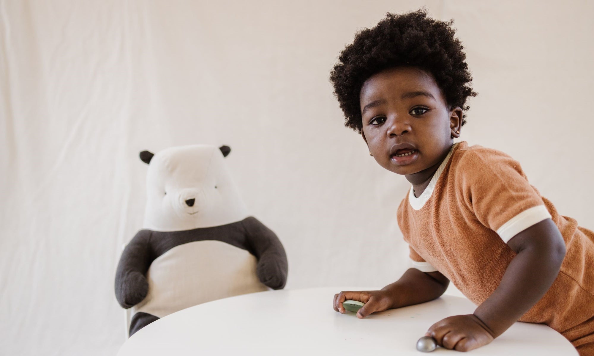 A child sitting next to a large Maileg Panda 