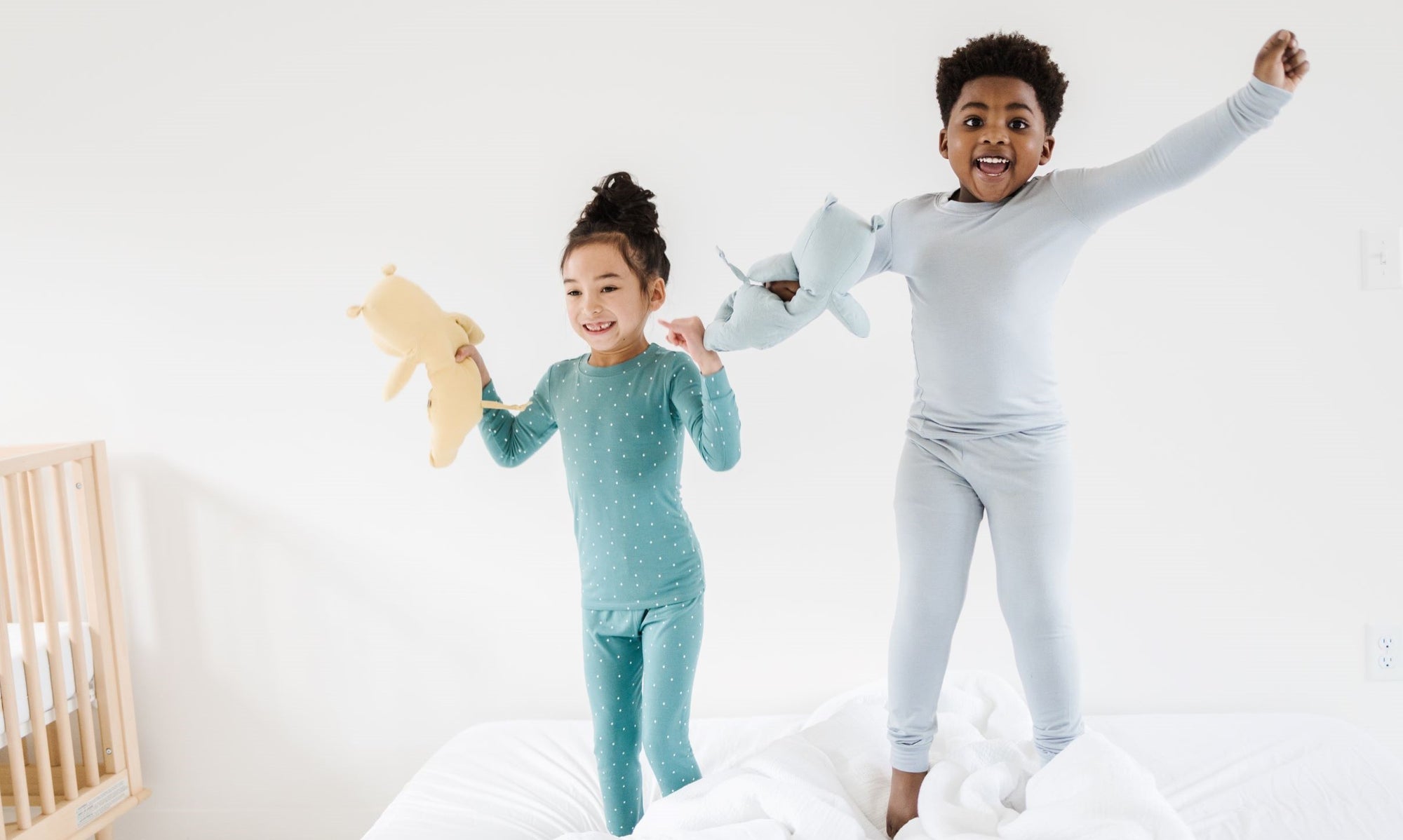 A boy and girl jumping on a bed in pj's