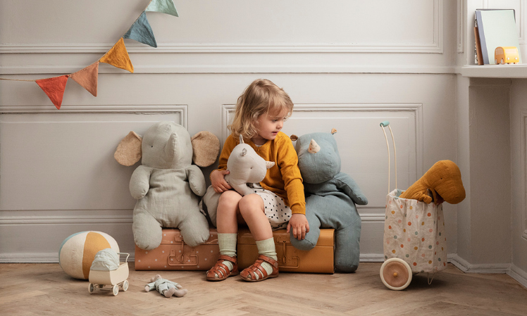 child sitting next to large Maileg soft toys