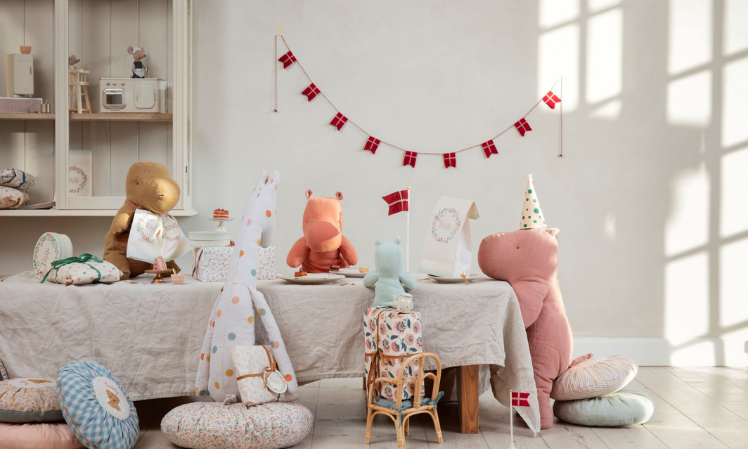 Maileg Safari Friends sitting around a long table wearing party hats. 