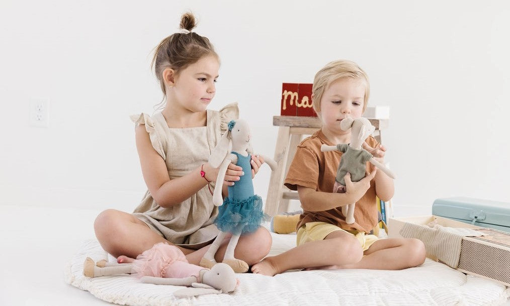 A girl playing with the Maileg Ballerina Bunny and a boy playing with the 